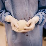 Cirurgião segura um implante mamário de silicone preparado para cirurgia.