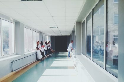 Profissionais de saúde caminham por um corredor de hospital.