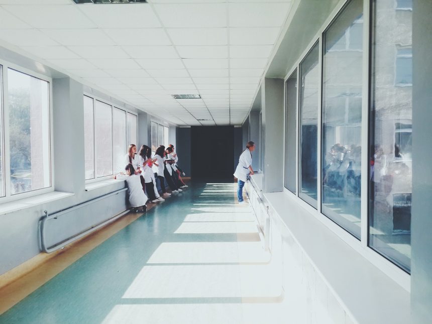 Profissionais de saúde caminham por um corredor de hospital.