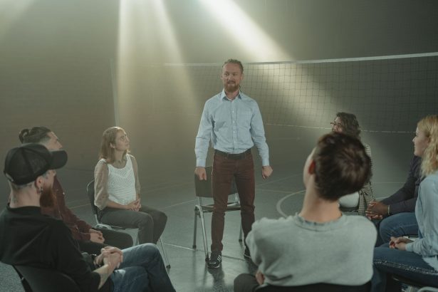 Grupo de pessoas participa de uma conversa de apoio sobre saúde mental em uma sala iluminada