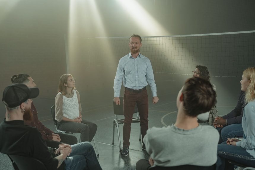 Grupo de pessoas participa de uma conversa de apoio sobre saúde mental em uma sala iluminada